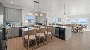 A modern kitchen with a large island, pendant lighting, and a view of the ocean. - Wavy Daze: New Construction, Private Pool, Pet Friendly, Gorgeous Beach Views (St Joe Beach)