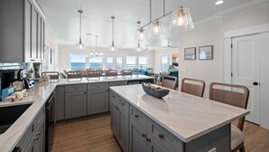 A modern kitchen with a large island, pendant lights, and a view of the ocean. - Wavy Daze: New Construction, Private Pool, Pet Friendly, Gorgeous Beach Views (St Joe Beach)