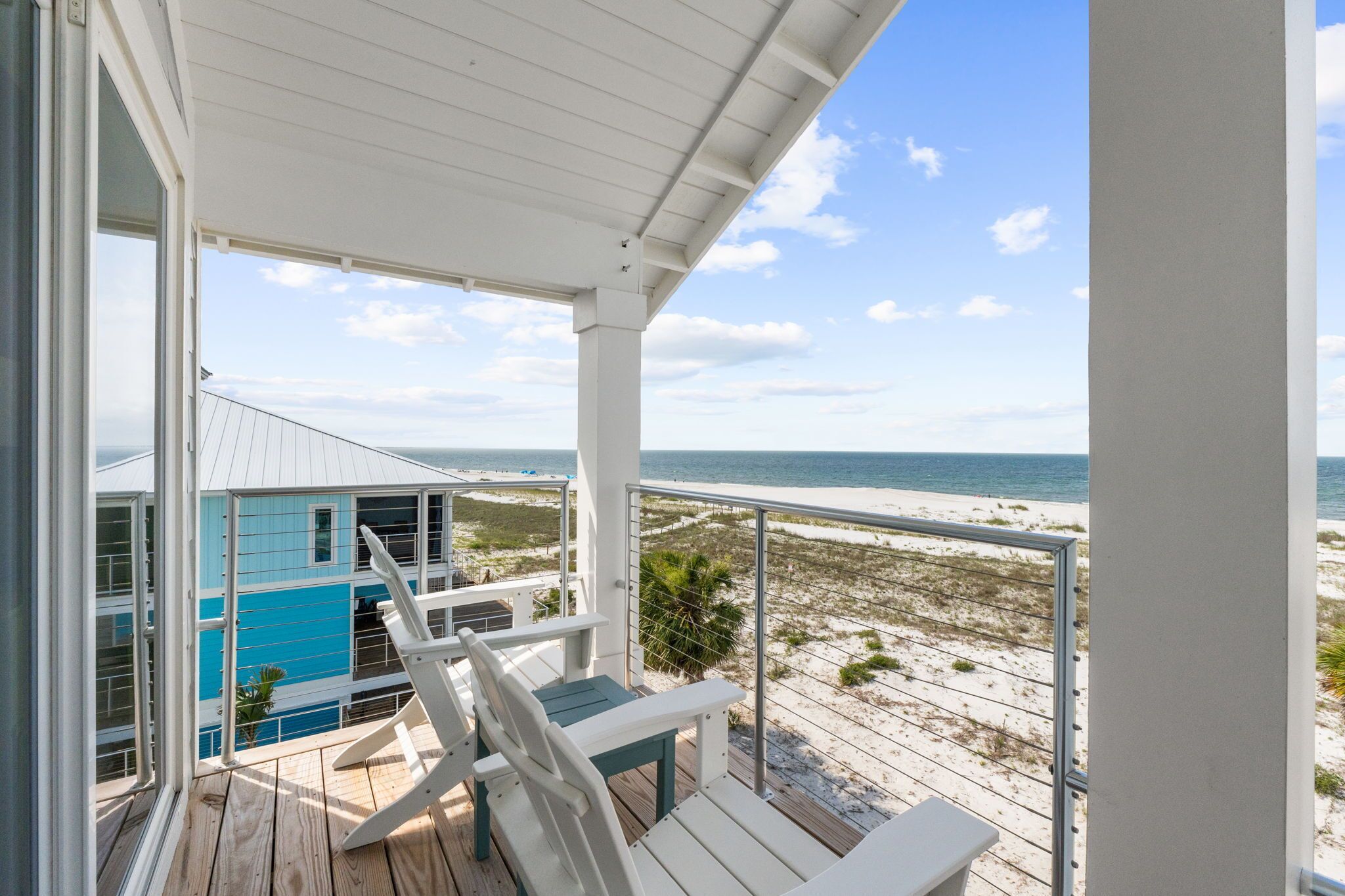 A beach house with a balcony overlooking the ocean.