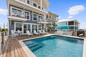 A multi-story building with a swimming pool, outdoor seating, and a separate structure with a blue roof.