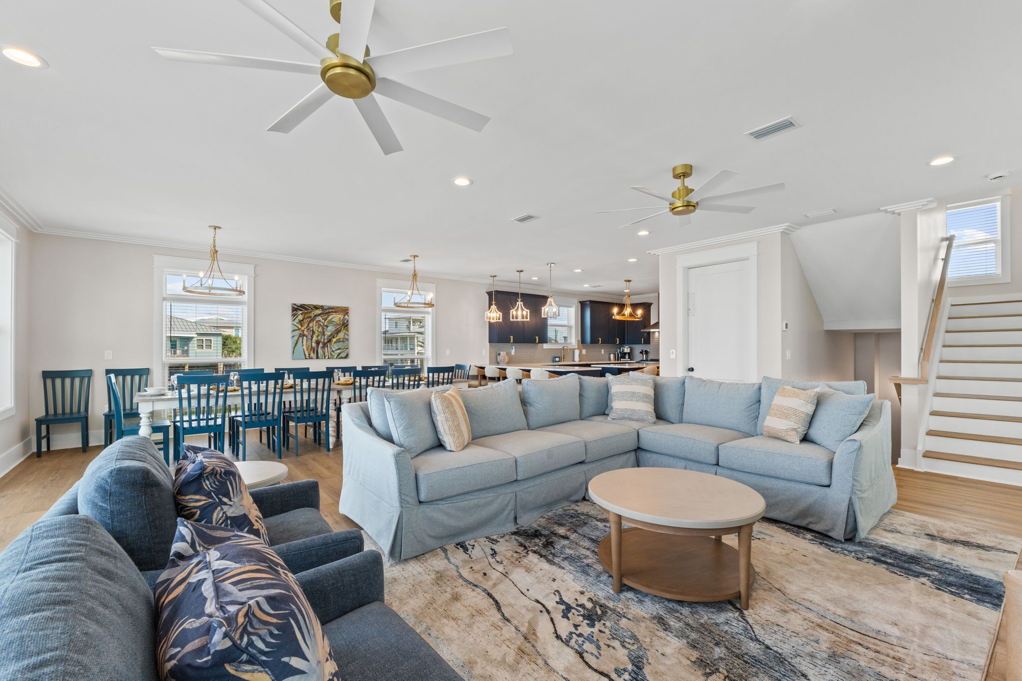 A spacious living room with a large L-shaped sectional sofa, a round coffee table, and a ceiling fan.