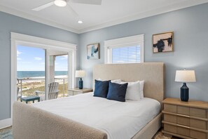 Ein Schlafzimmer mit einem großen Bett, zwei Nachttischen, einem Deckenventilator und Blick auf den Strand.