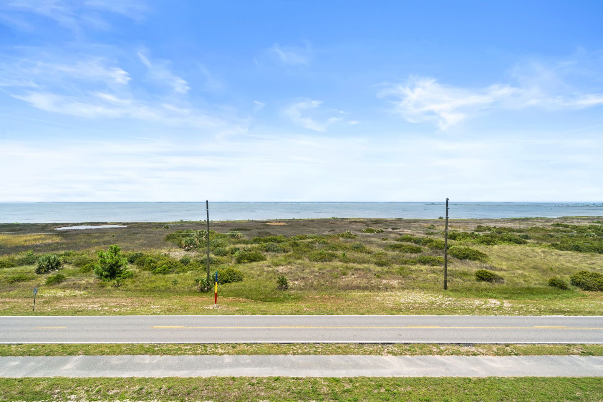 A coastal road with a grassy landscape and a clear sky.