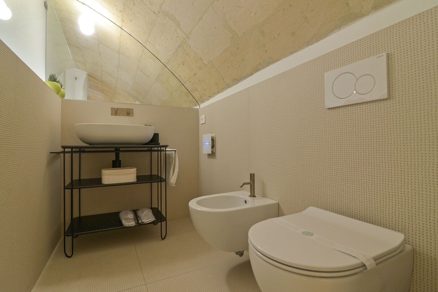 A compact bathroom with a vessel sink, bidet, and toilet.