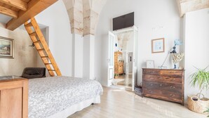 Een slaapkamer met een bed, een houten dressoir en een ladder naar een hoger niveau.