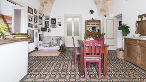 Een gezellig interieur met een betegelde vloer, een houten eettafel met stoelen, een bank en een boekenkast.