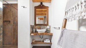 Een badkamer met een houten wastafelmeubel, een witte wasbak en een spiegel.