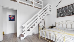 Ein Schlafzimmer mit einem Bett, einer weißen Wendeltreppe und einer Tafel an der Wand.