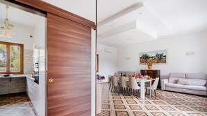 A modern living room with a dining area, patterned flooring, and a painting on the wall.