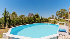 An outdoor swimming pool with a clear blue water, surrounded by trees and a wooden deck.