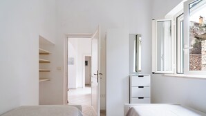 A bedroom with two beds, a wardrobe, a mirror, and a window.