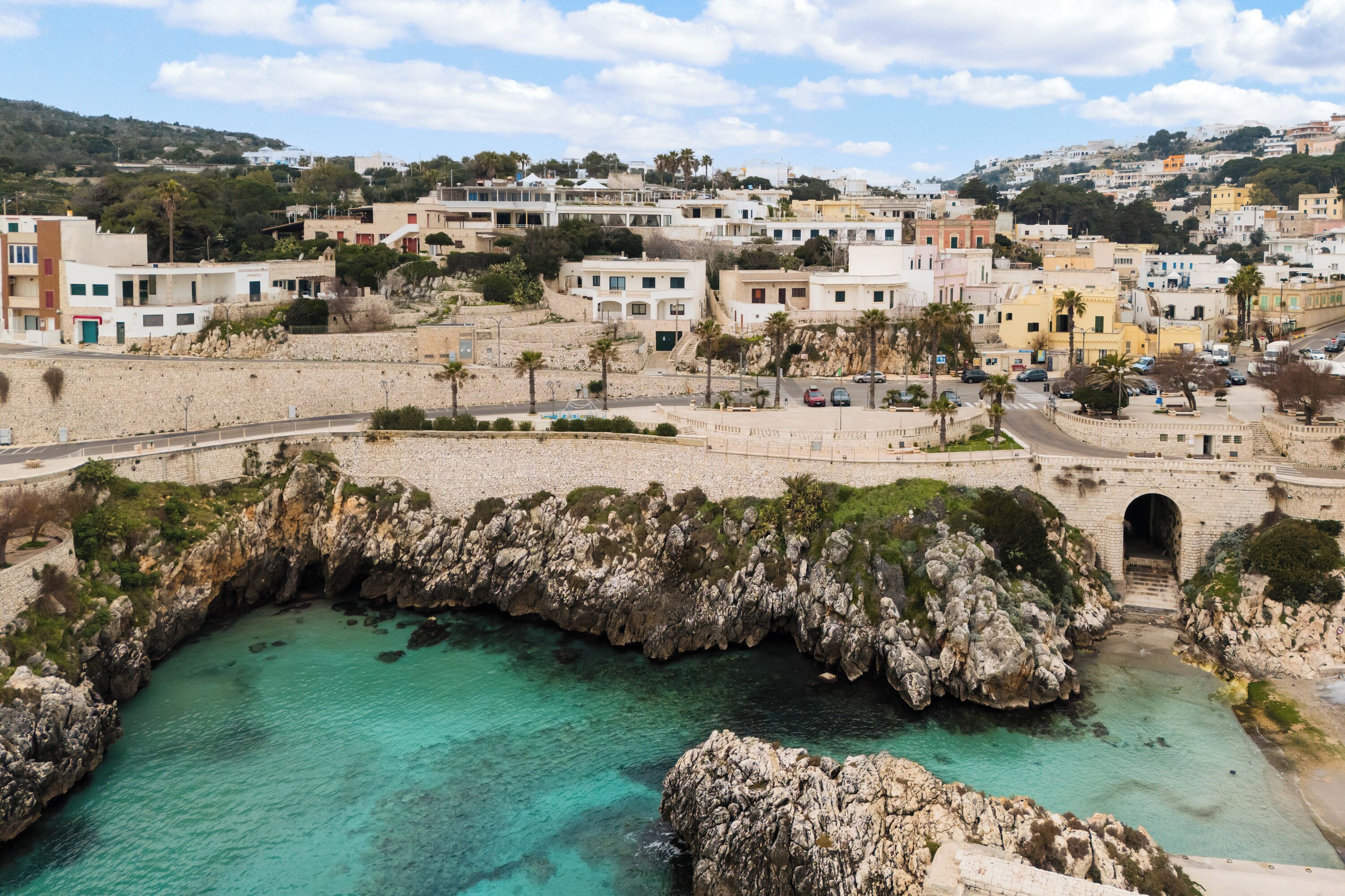 A coastal town with a rocky bay, a bridge, and buildings with balconies.