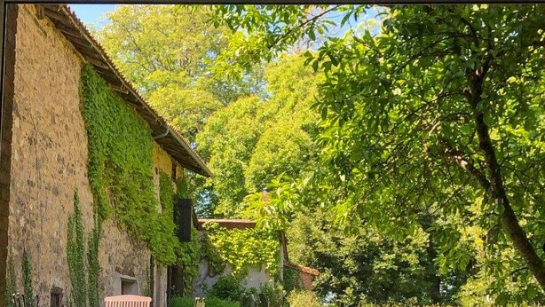 A view through a window of a rustic building with a stone wall and a wooden table with chairs. - Le Florentin - Spacious Family Home in a Peaceful Village near Limoges (Condat-sur-Vienne)