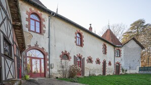 A historic building with multiple arched windows and a red door. - Le Florentin - Spacious Family Home in a Peaceful Village near Limoges (Condat-sur-Vienne)