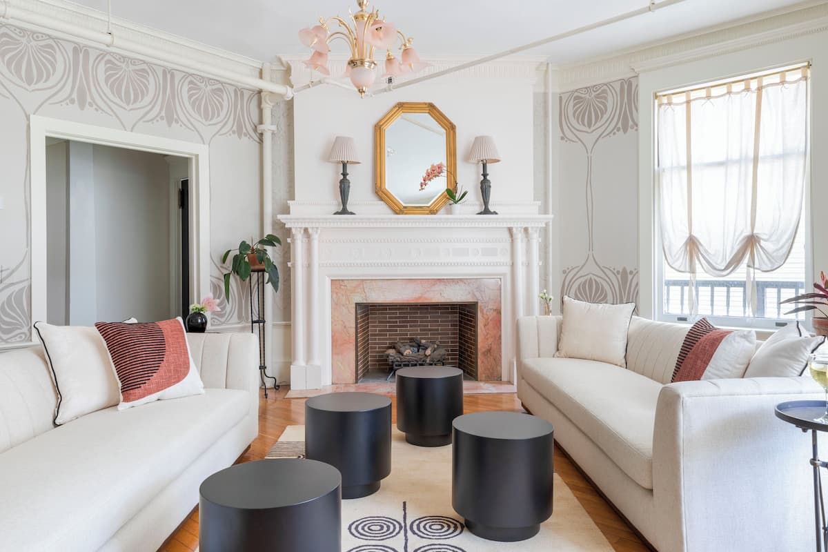 A living room with a fireplace, two sofas, and four black side tables.