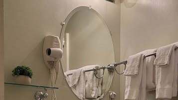 A bathroom with a toilet, bidet, sink, and a mirror with a towel rack.