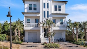 A two-story house with a garage, a balcony, and a well-maintained garden with palm trees. - Blue Water Paradise! NEW PRIVATE POOL! 6-bdrm near beaches, restaurants, 8 bikes (Santa Rosa Beach)