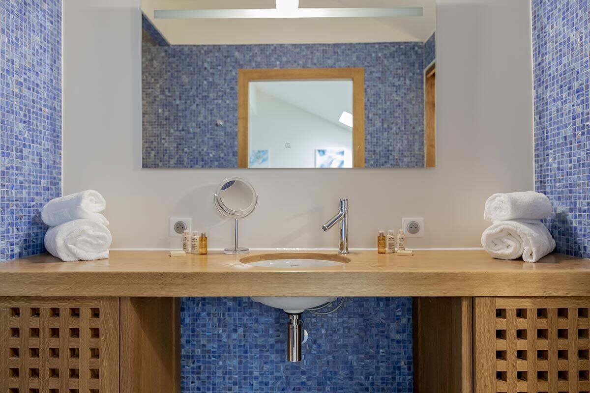 Un baño con tocador de madera, un lavamanos, un espejo y dos toallas.