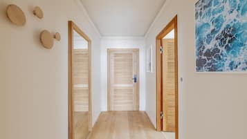 Un pasillo con puertas de madera, piso de madera y una obra de arte colgada en la pared.
