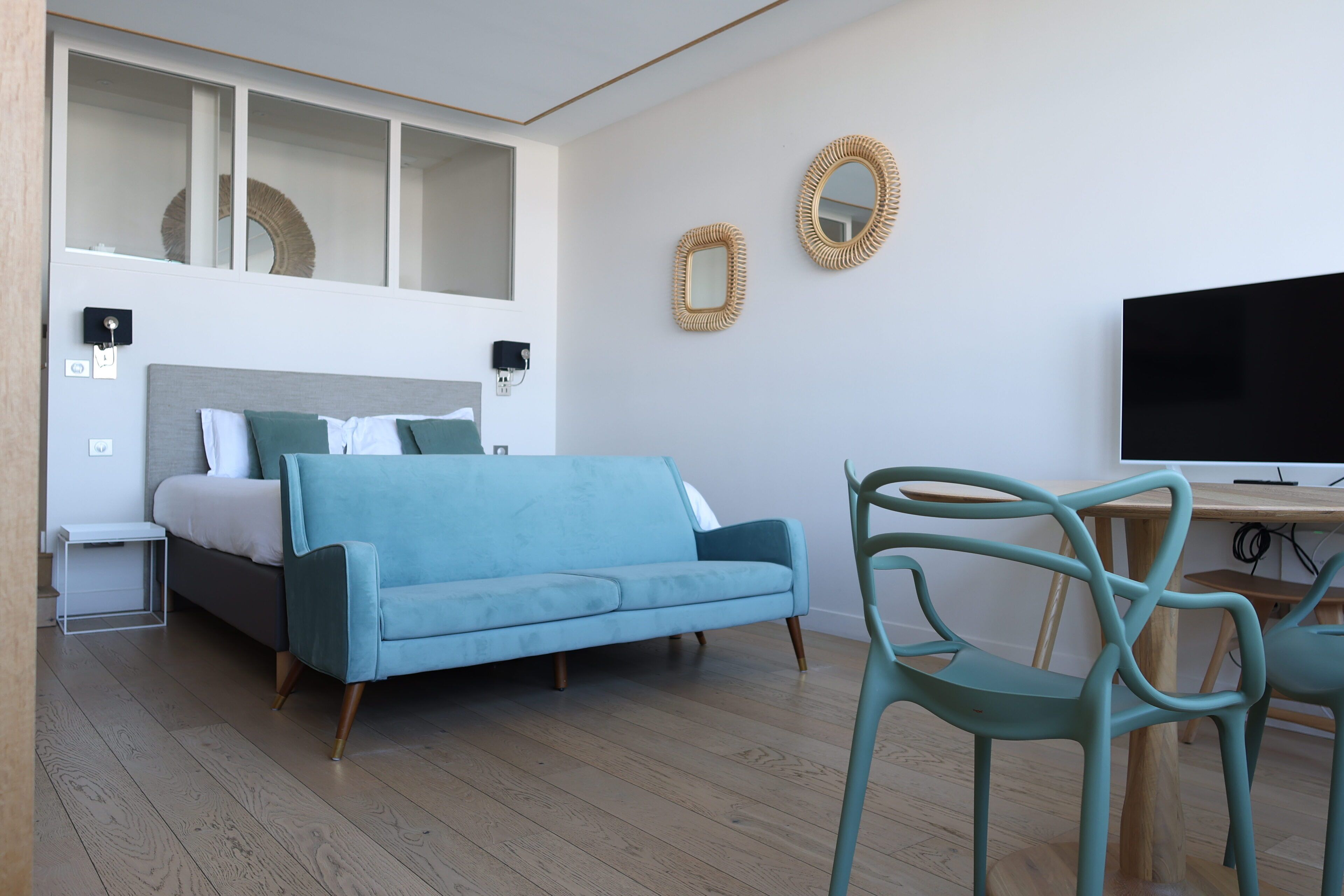 Une chambre moderne avec un lit, un canapé bleu, une télévision et un plancher en bois.