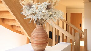 Una escalera de madera con un jarrón de flores blancas sobre una plataforma blanca.