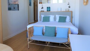 Un dormitorio con una cama grande, una mesita de noche, una silla, un espejo y una pared decorada con un cuadro.