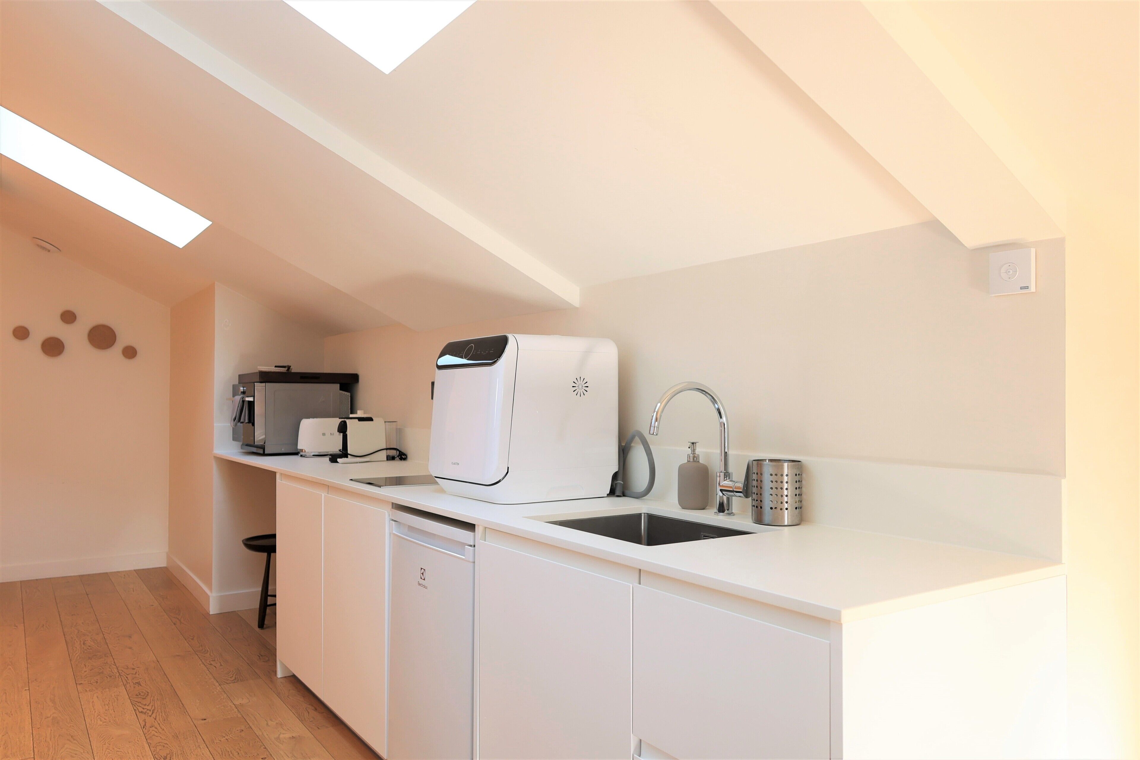 A modern kitchen with a dishwasher, a coffee machine, and a sink.