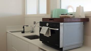 Cocina compacta con lavavajillas integrado, un fregadero y una ventana sobre la encimera.