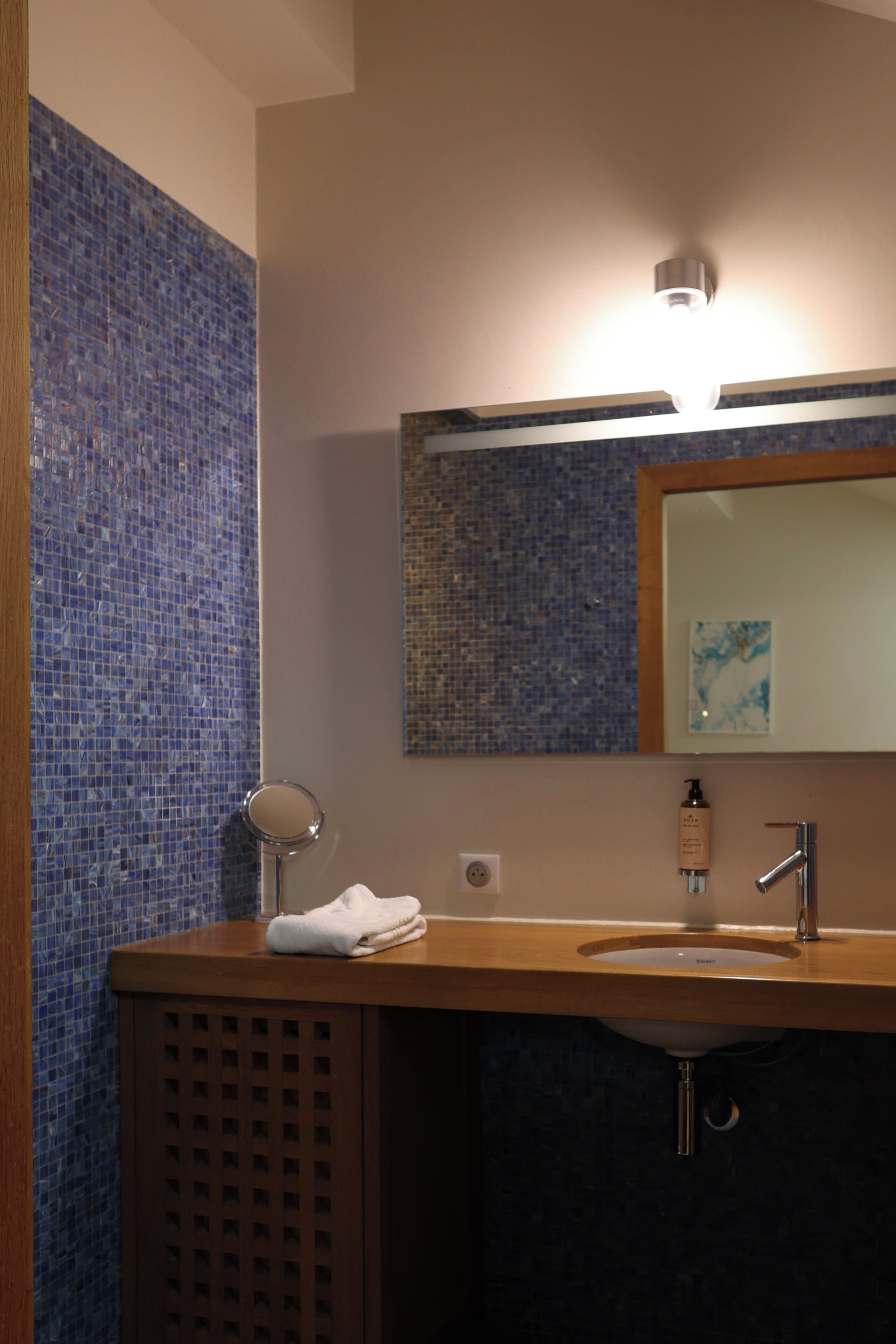 Une salle de bain avec un lavabo, un miroir et des carreaux de mosaïque bleus.