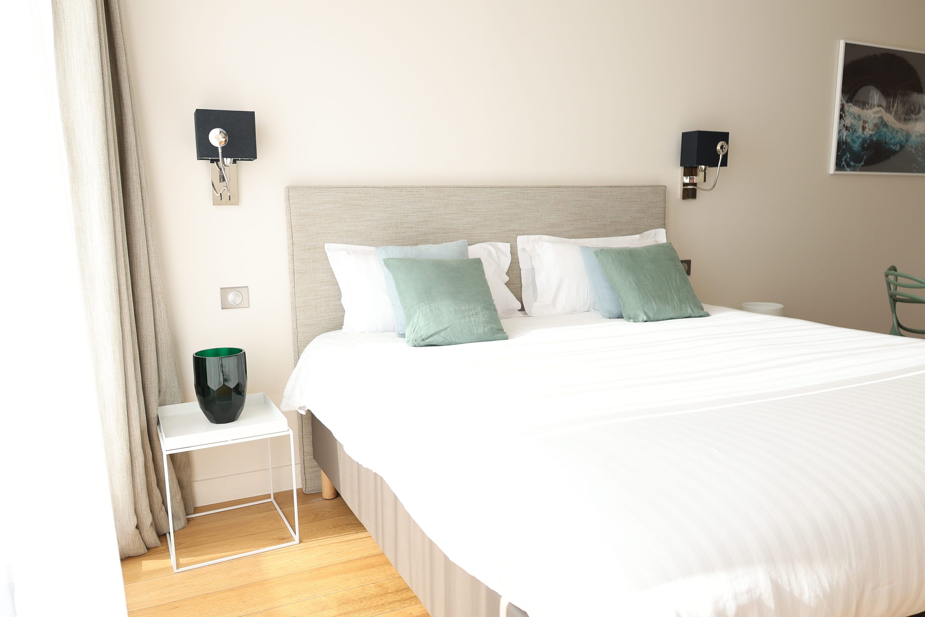 Ein ordentlich eingerichtetes Hotelzimmer mit einem großen Bett, Nachttischen und Wandleuchten.
