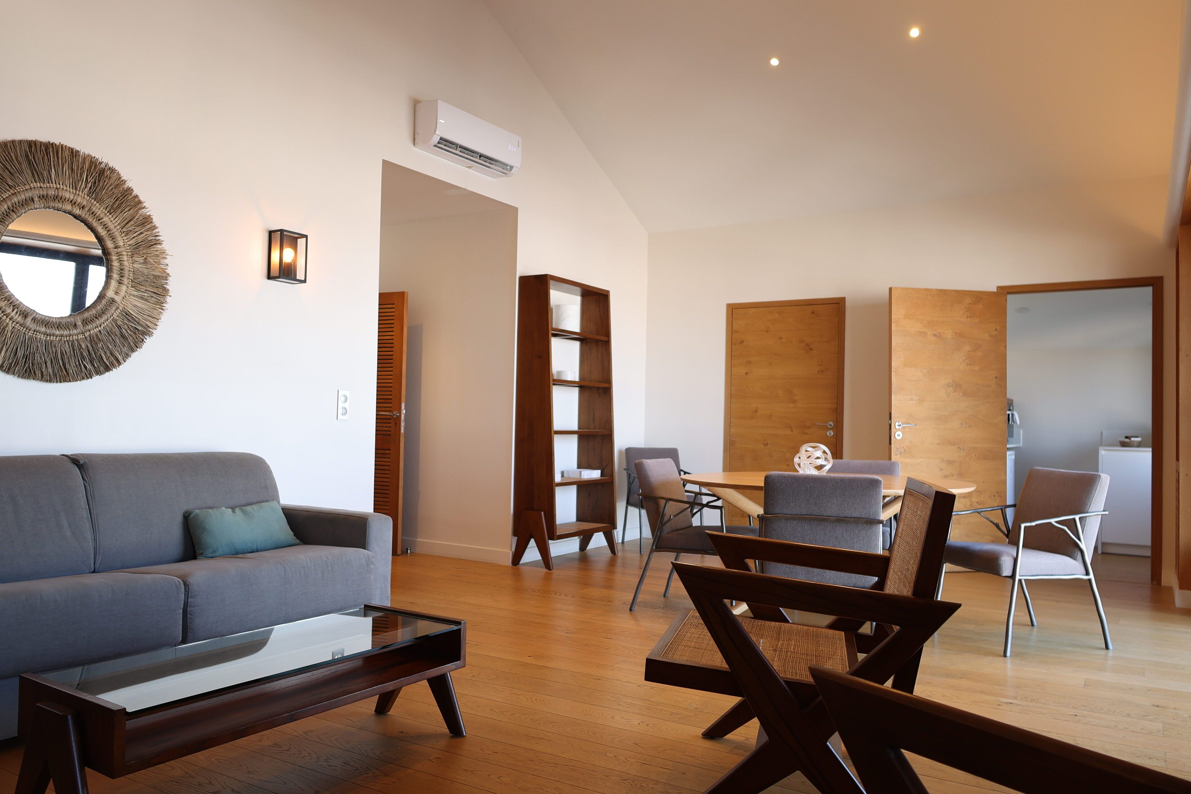 A modern living room with a sofa, coffee table, and dining area with chairs.