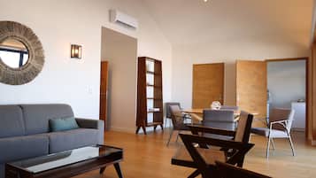 A modern living room with a sofa, coffee table, and dining area with chairs.