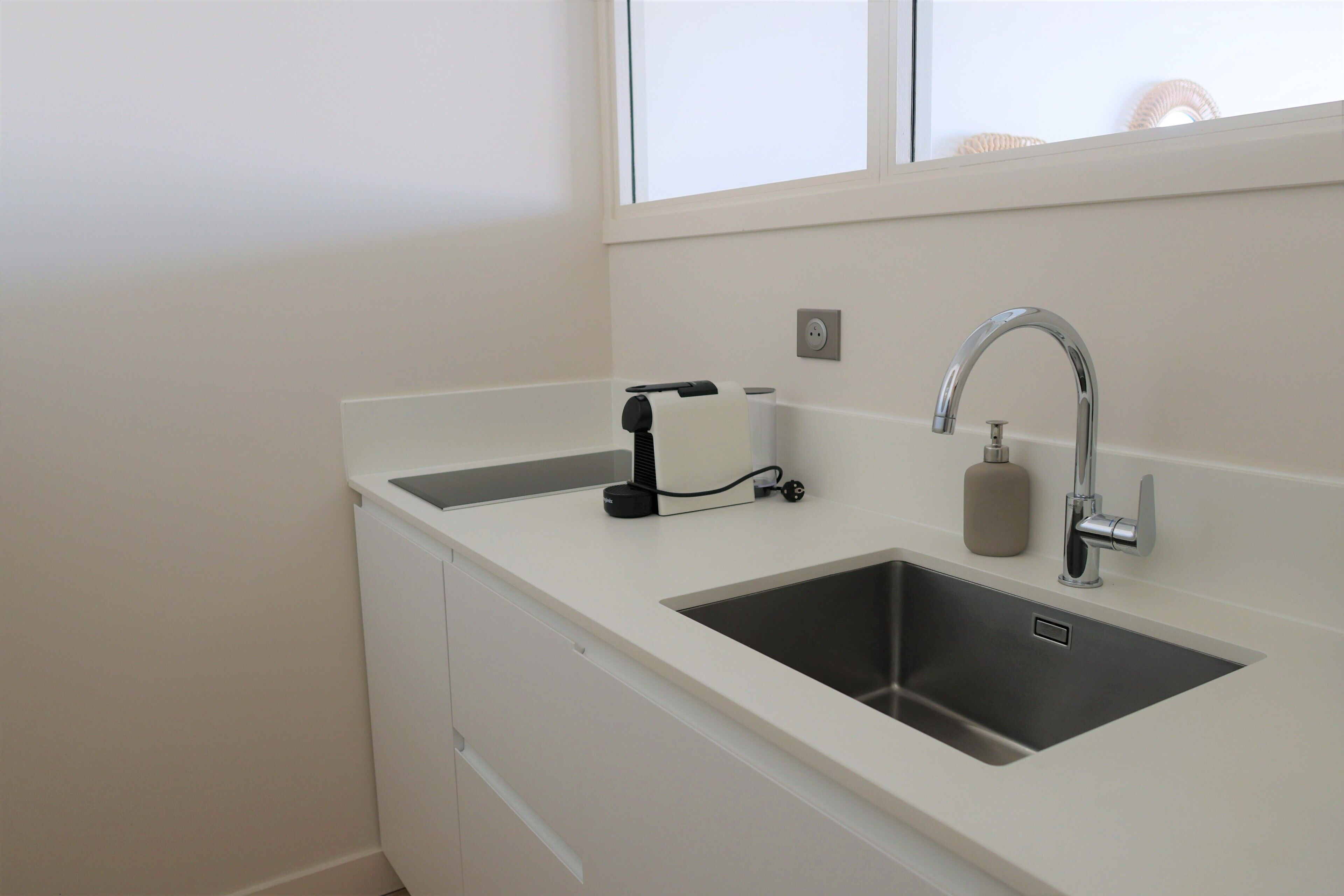 A modern kitchen with a stainless steel sink, a faucet, a soap dispenser, and a paper towel holder.