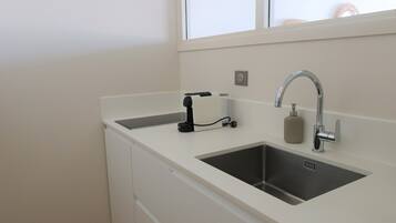 A modern kitchen with a stainless steel sink, a faucet, a soap dispenser, and a paper towel holder.