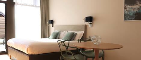 Habitación de hotel con cama, dos lámparas de pared, una mesa con sillas y un cuadro en la pared.