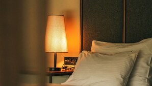 A neatly made bed with white linens, a bedside table with a lamp and a radio, and a dark headboard. - Casa Vera Villa (Sapanca)