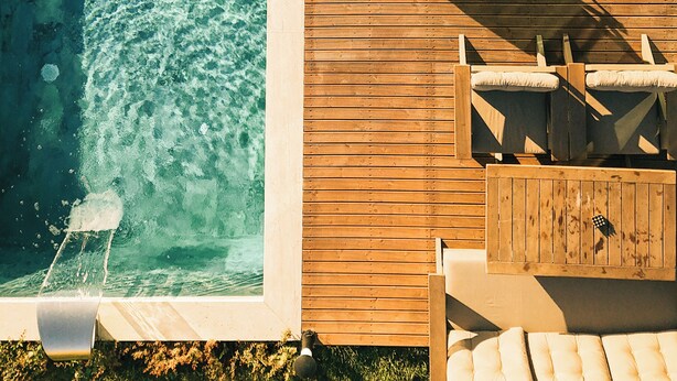 A swimming pool with a wooden deck, lounge chairs, and a table. - Casa Vera Villa (Sapanca)