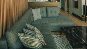 A modern living room with a sectional sofa, a small coffee table, and a view of the kitchen and upper floor. - Casa Vera Villa (Sapanca)