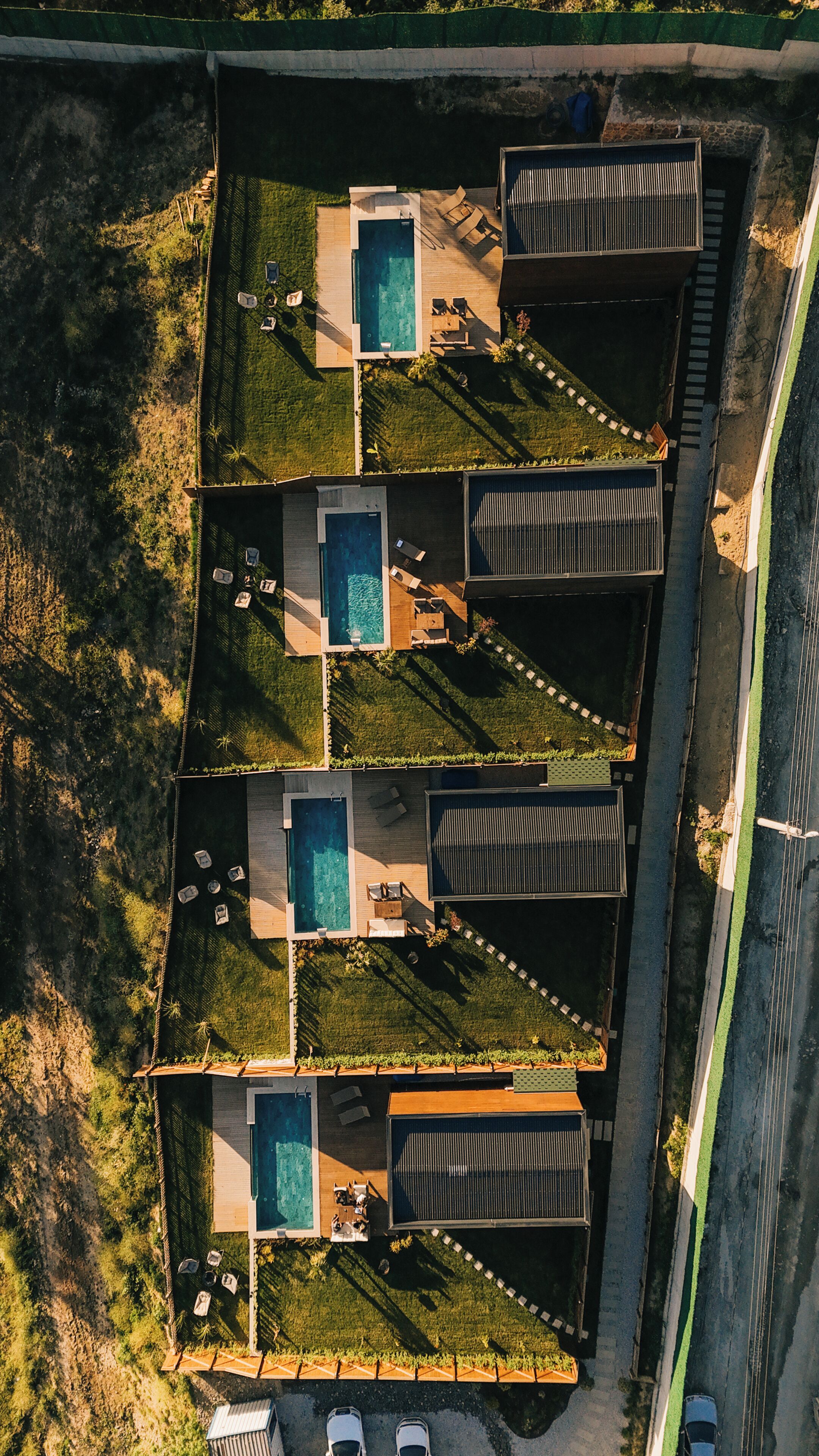 Vista aérea de um complexo residencial com várias piscinas, cada uma com um deck e espreguiçadeiras.