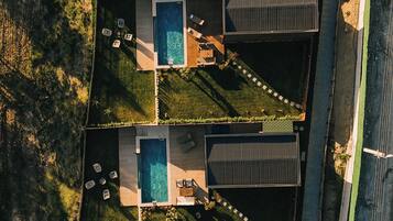 Vista aérea de um complexo residencial com várias piscinas, cada uma com um deck e espreguiçadeiras.