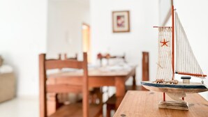 A model sailboat on a wooden table in a room with a wooden dining table and chairs.