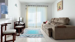 A living room with a sofa, two chairs, a TV, and a water dispenser.
