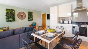 Una cocina moderna con armarios blancos, una campana extractora de acero inoxidable y un horno Bosch.