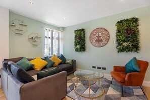 Una sala de estar con un sofá, un sillón y una mesa de centro de vidrio.
