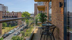 Een balkon met uitzicht op een stadsstraat, een tafel en stoelen.