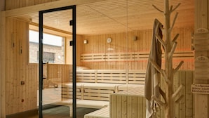 Eine Holzsauna mit Bänken und einer Glastür, die nach draußen führt.