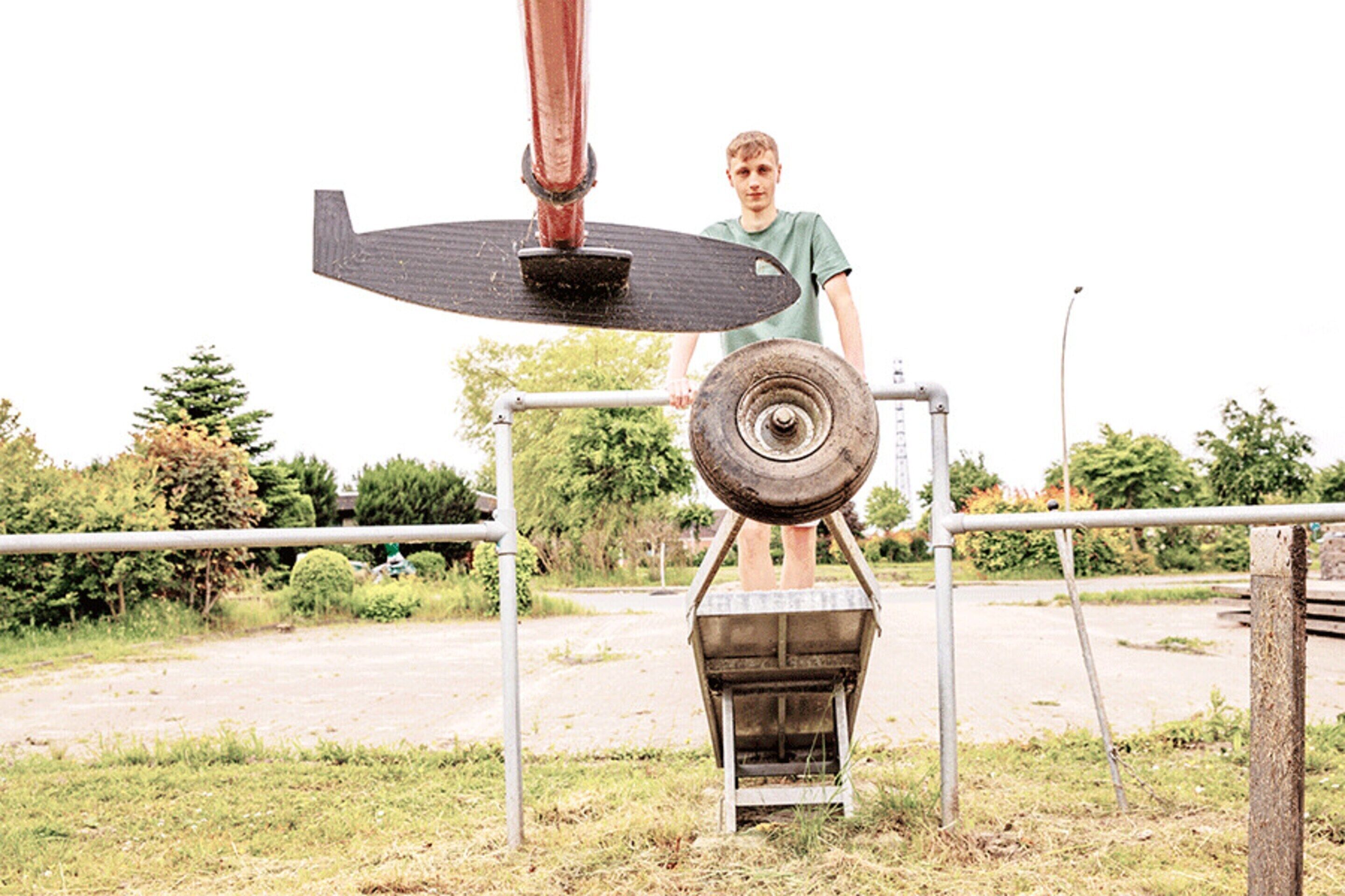 A person standing next to a mechanical device outdoors.