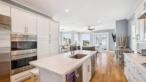 A modern kitchen with white cabinetry, stainless steel appliances, and a large island with a sink.
