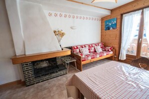 Ein gemütliches Zimmer mit Kamin, einer Couch mit gemusterten Kissen und einem Bett mit kariertem Überwurf.