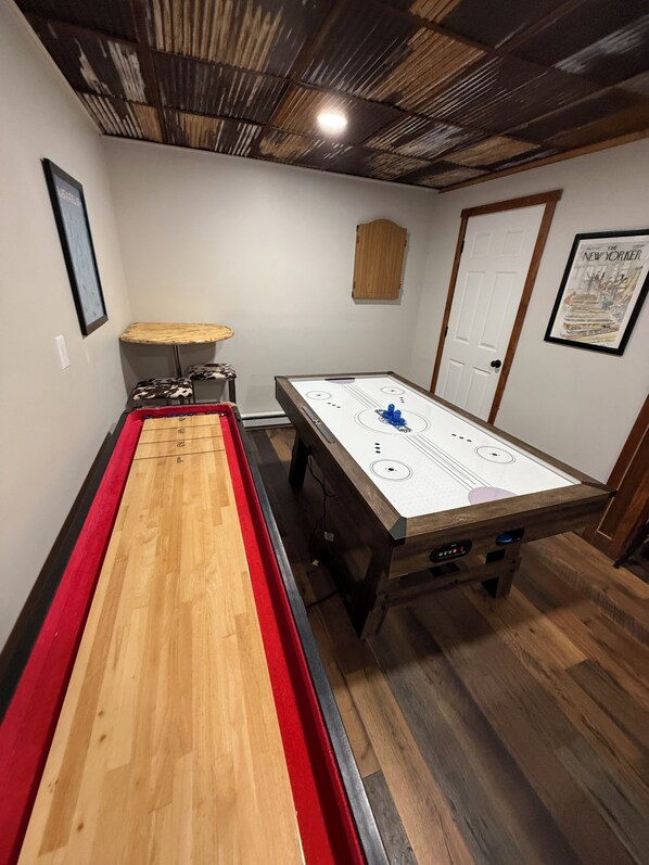 Una habitación con una mesa de juego de salón, un banco de madera y una puerta.